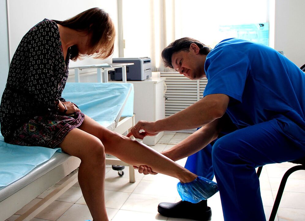 doctor examines leg with varicose veins